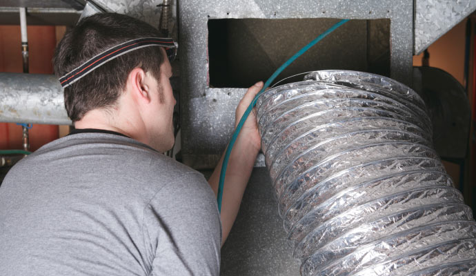Technician cleaning air duct vent