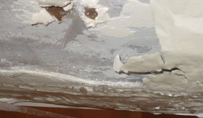 Peeling paint and bulging wall at ceiling area