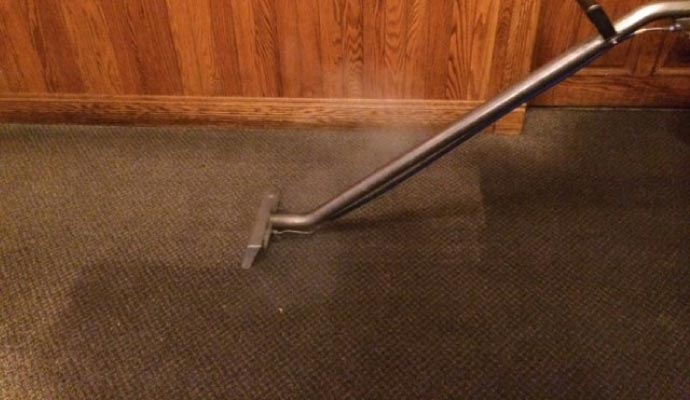 Person cleaning carpet with equipment