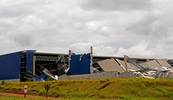 A warehouse with significant structural damage caused by a storm.