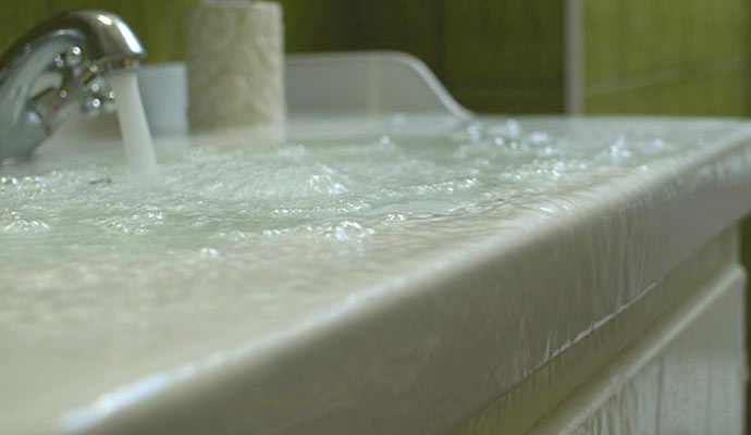Overflowing bathroom sink filled with water due to an open faucet